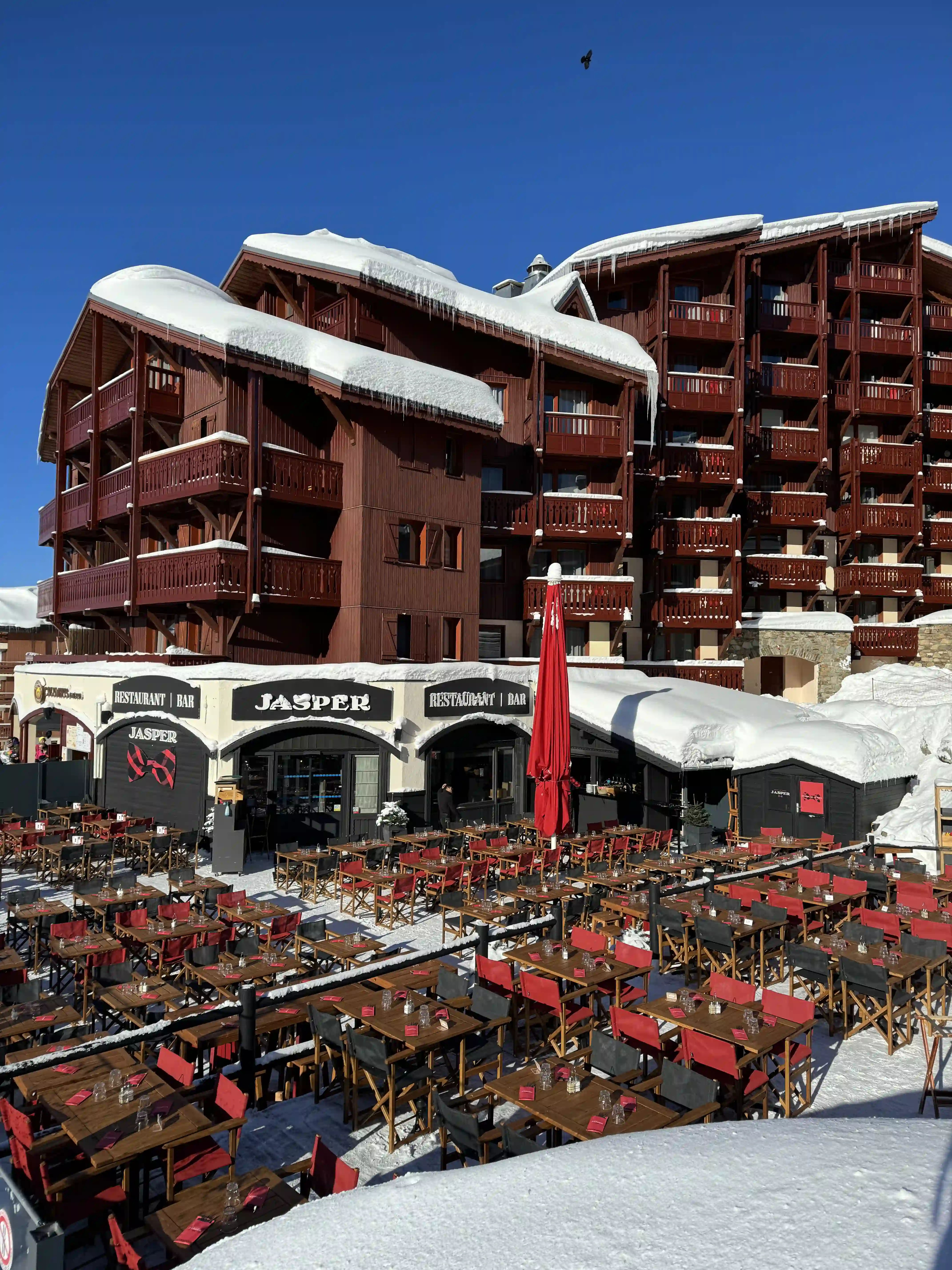Restaurant Jasper and its large terrace set up with tables and chairs, completely covered in snow under the sun.