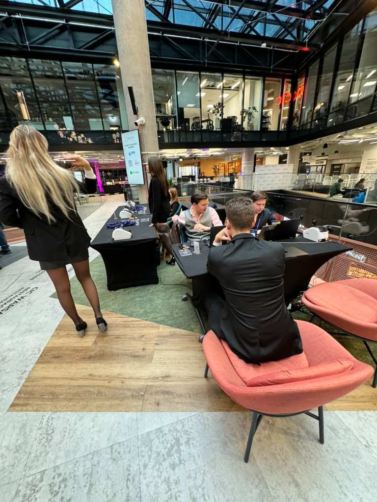 Ludzie rozmawiają przy stołach w nowoczesnym, przeszklonym biurze coworkingowym.