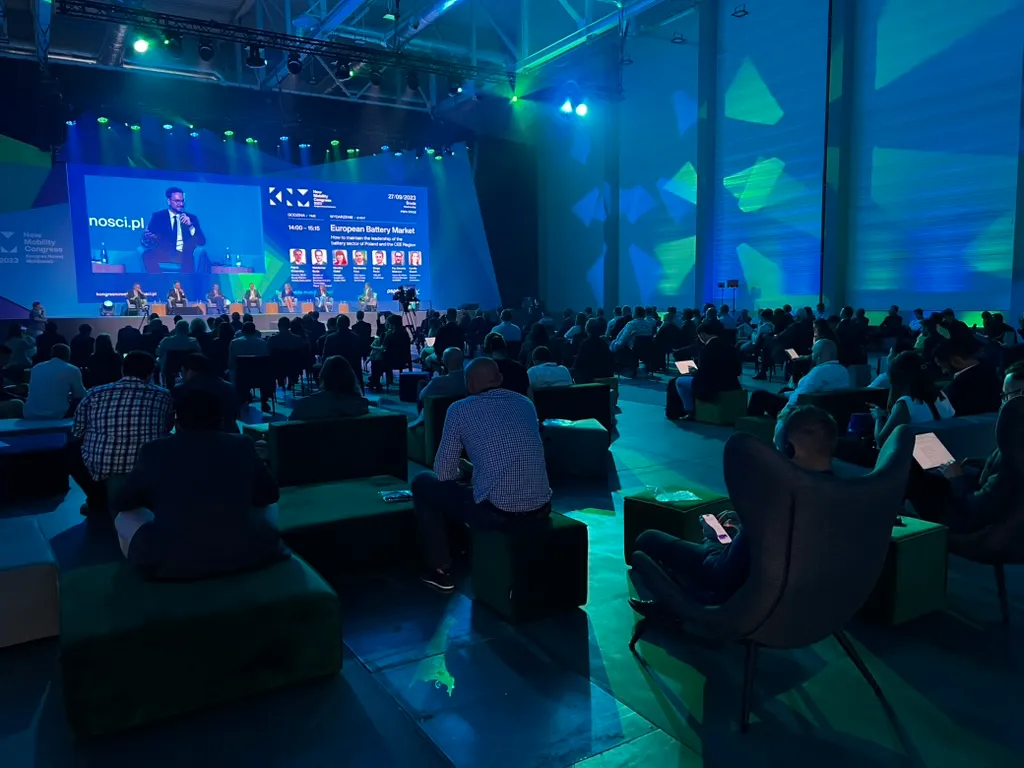 Uczestnicy siedzący w sali konferencyjnej z widokiem na scenę, gdzie odbywa się panel dyskusyjny o europejskim rynku baterii.