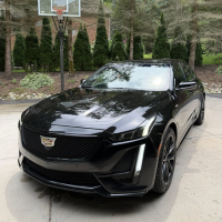 Burger with fried fries on black plate with sauce on the side