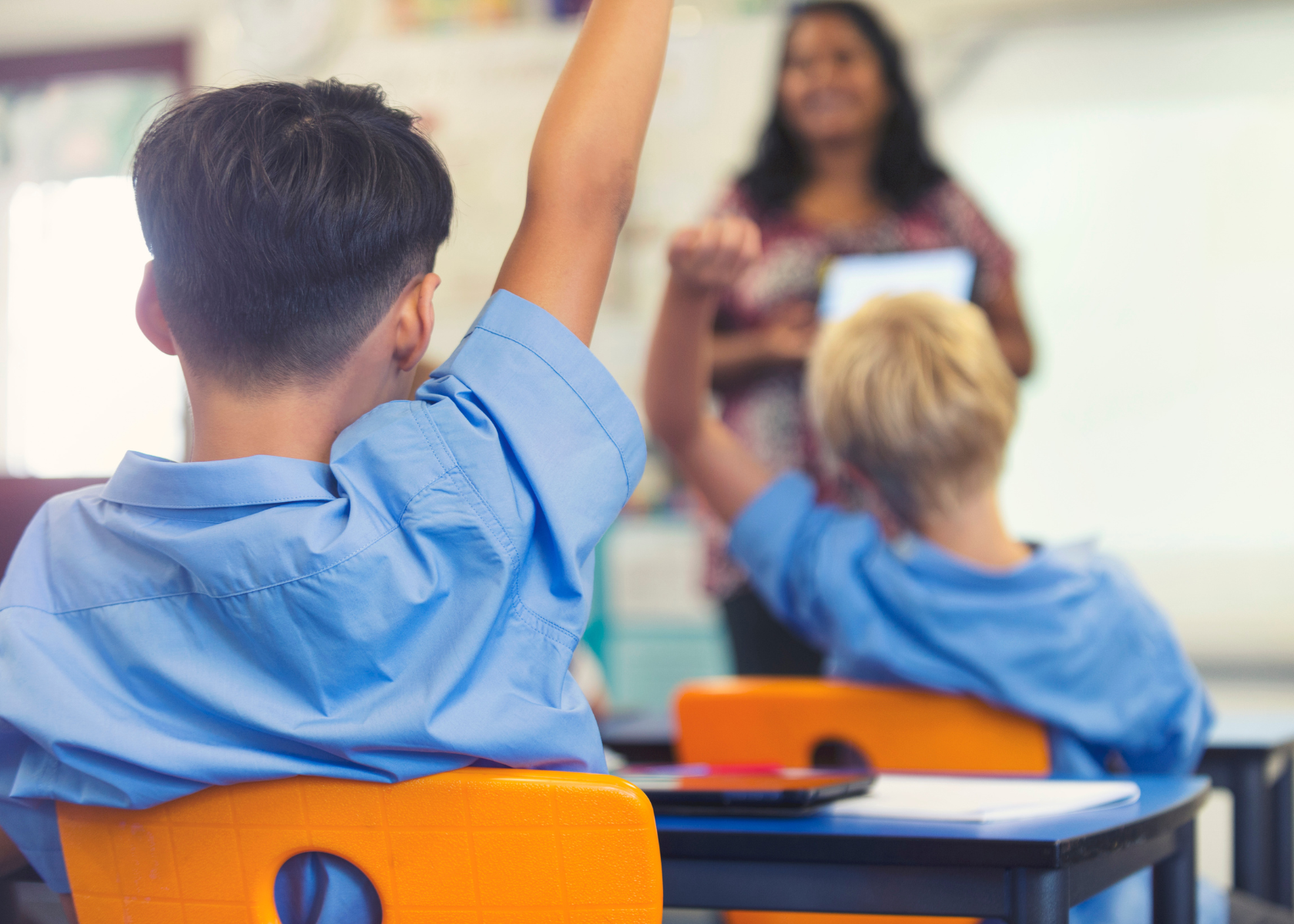 Students raising hands in classroom during Selective School test preparation lesson.