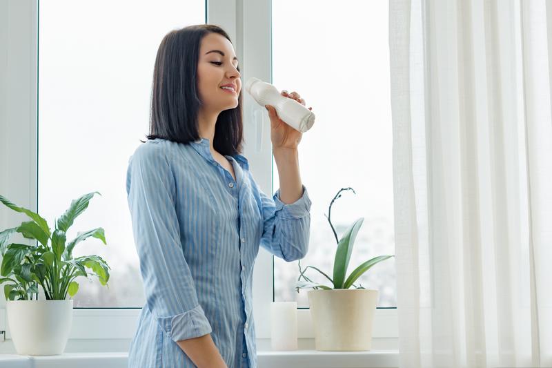 Frau genießt ein Wellnessgetränk in einer hellen, modernen Umgebung.