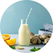 Glass bottle of creamy yogurt drink with orange, ginger and mint on a light blue background