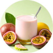 Glass of passion fruit yogurt drink surrounded by halved passion fruits and a leaf