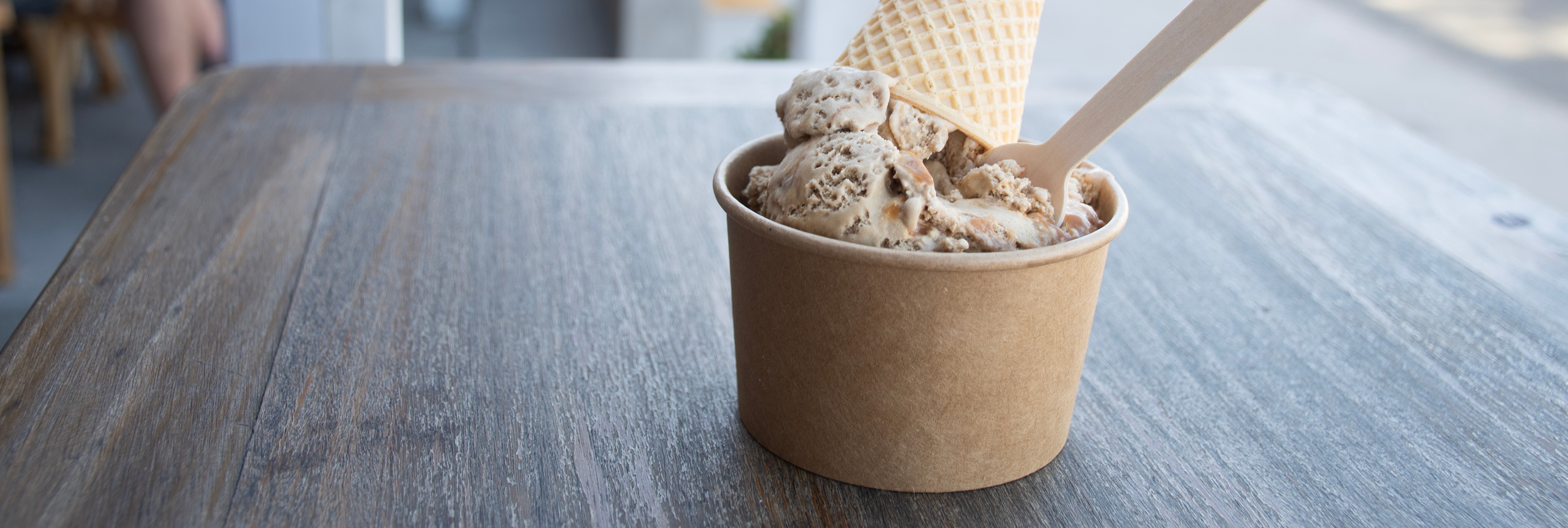 Cup of ice cream with a waffle cone garnish on a wooden table