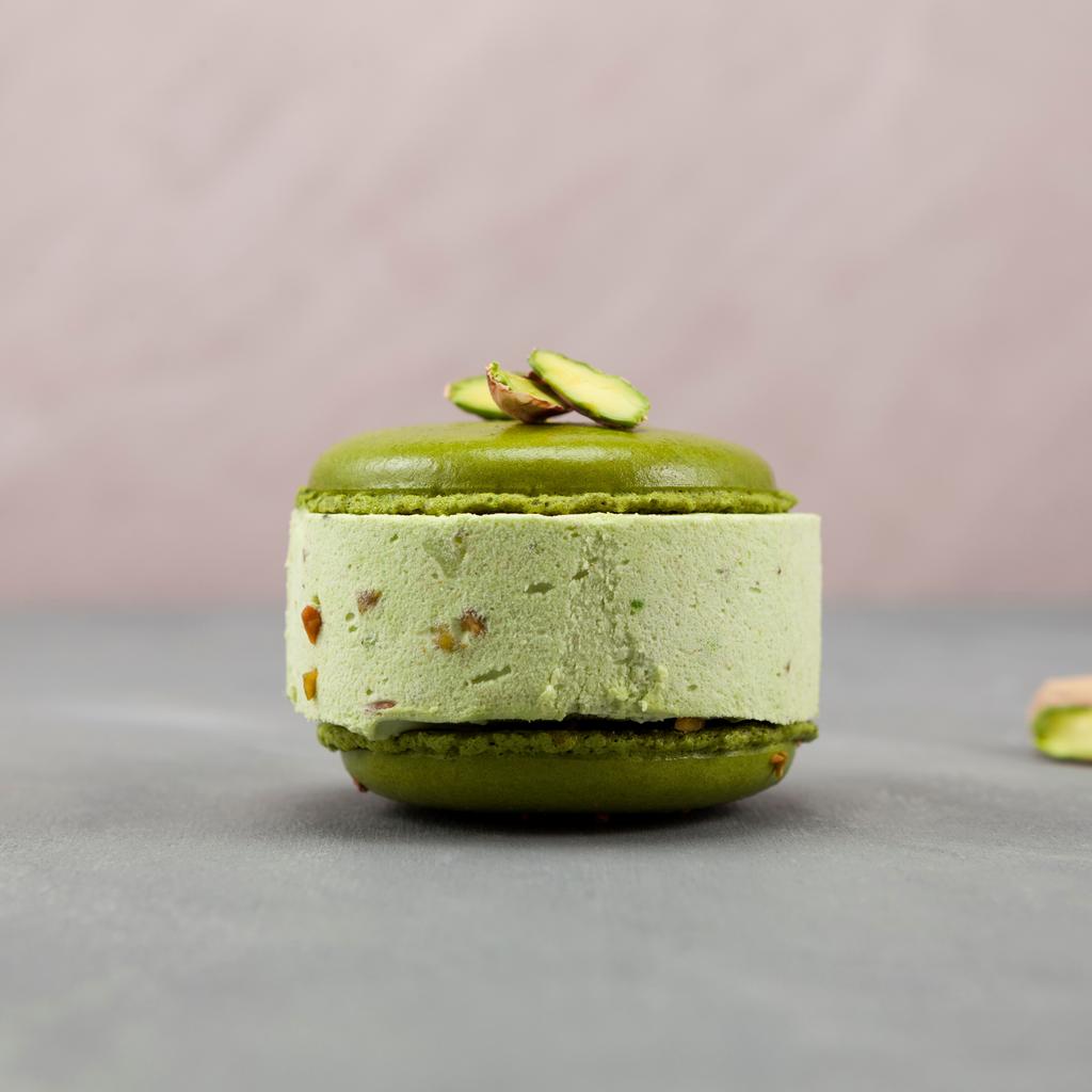 Grünes Macaron mit Pistaziencreme-Füllung und gehackten Pistazien als Topping.