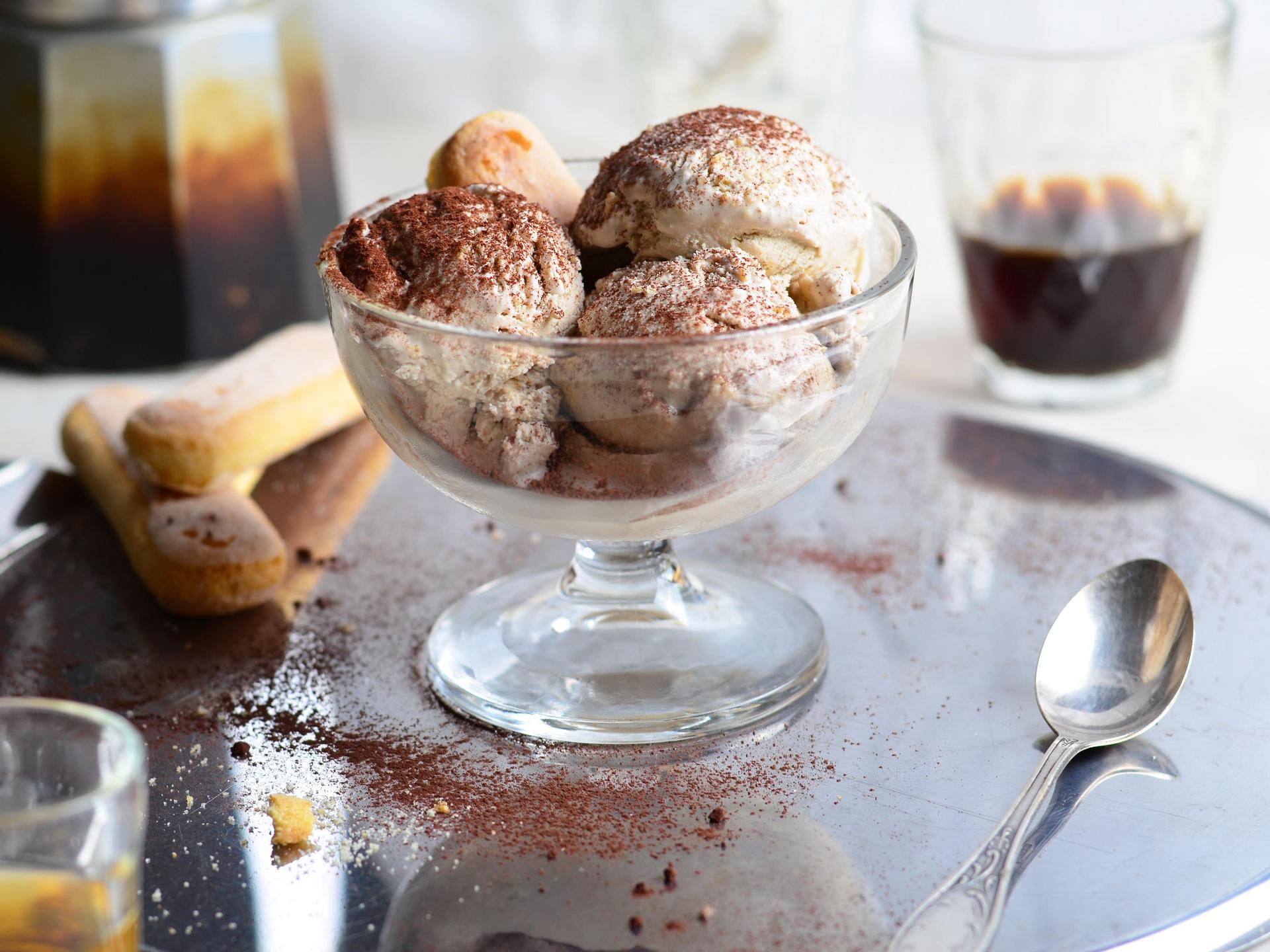 Glasschale mit Tiramisu-Eiskugeln bestäubt mit Kakao, serviert mit Kaffee und Löffelbiskuits