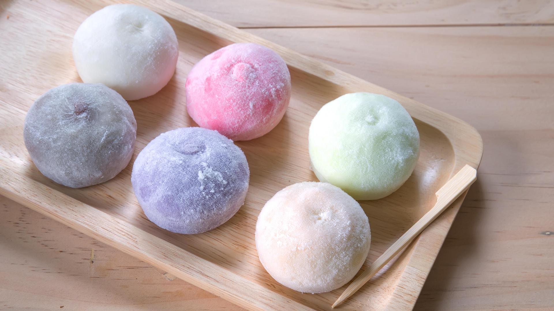 Assortment of colorful mochi rice cakes on a wooden tray