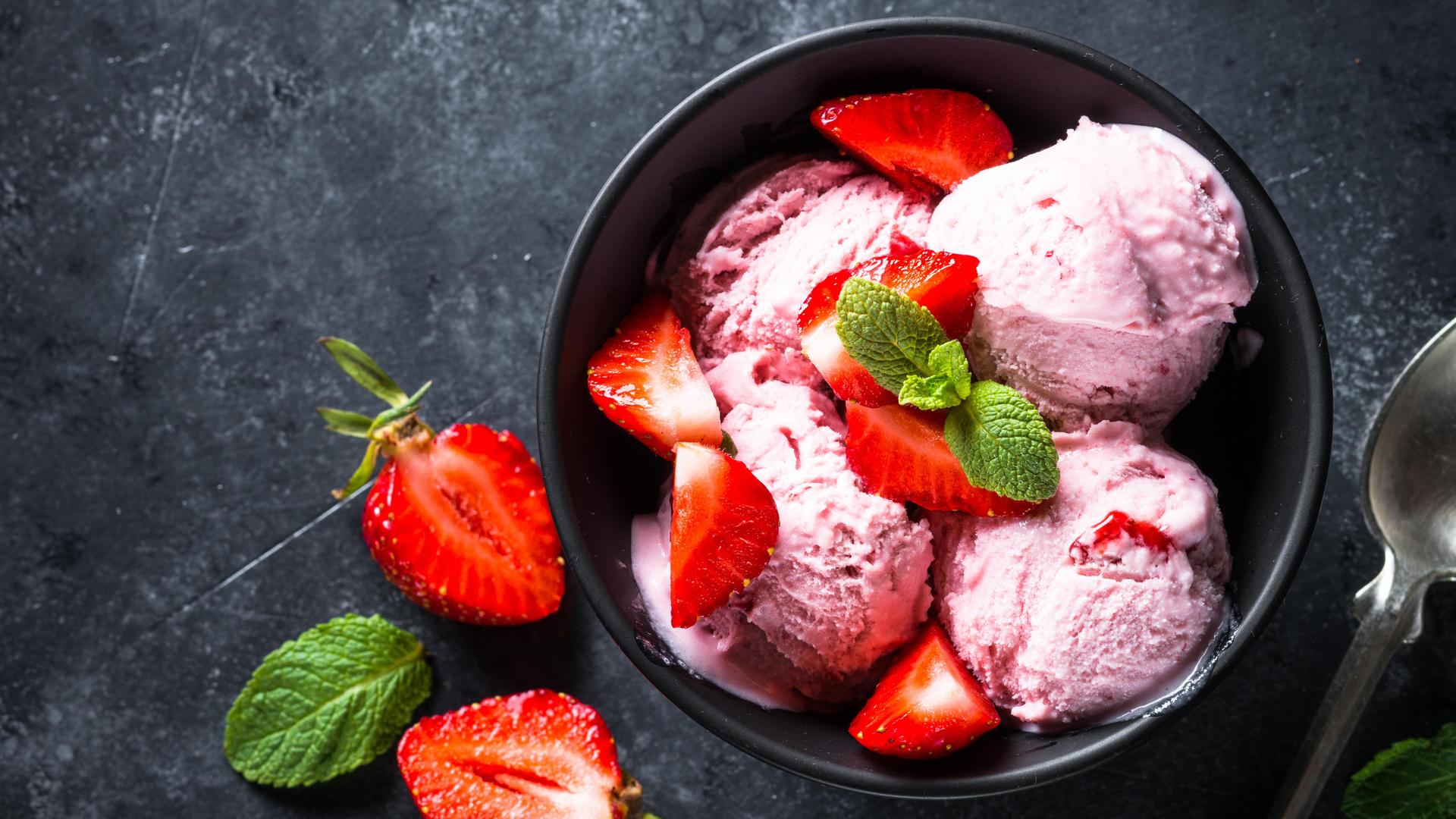 Bowl of strawberry ice cream topped with fresh strawberries and mint