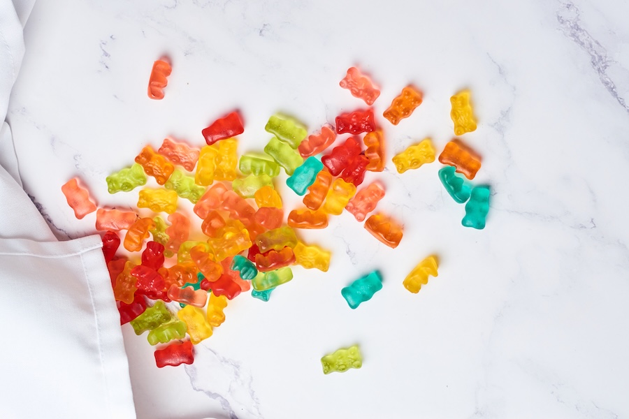 Bunte Gummibärchen verstreut auf weißem Marmor neben einem weißen Tuch