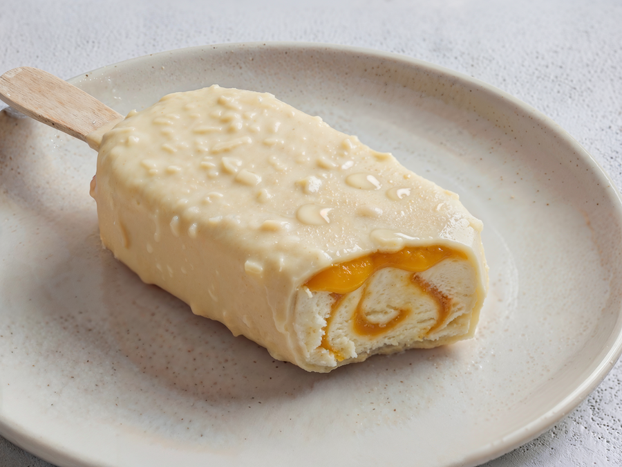 Eis am Stiel mit weißer Schokolade und Mandelstückchen, aufgeschnitten mit Mango-Swirl im Inneren