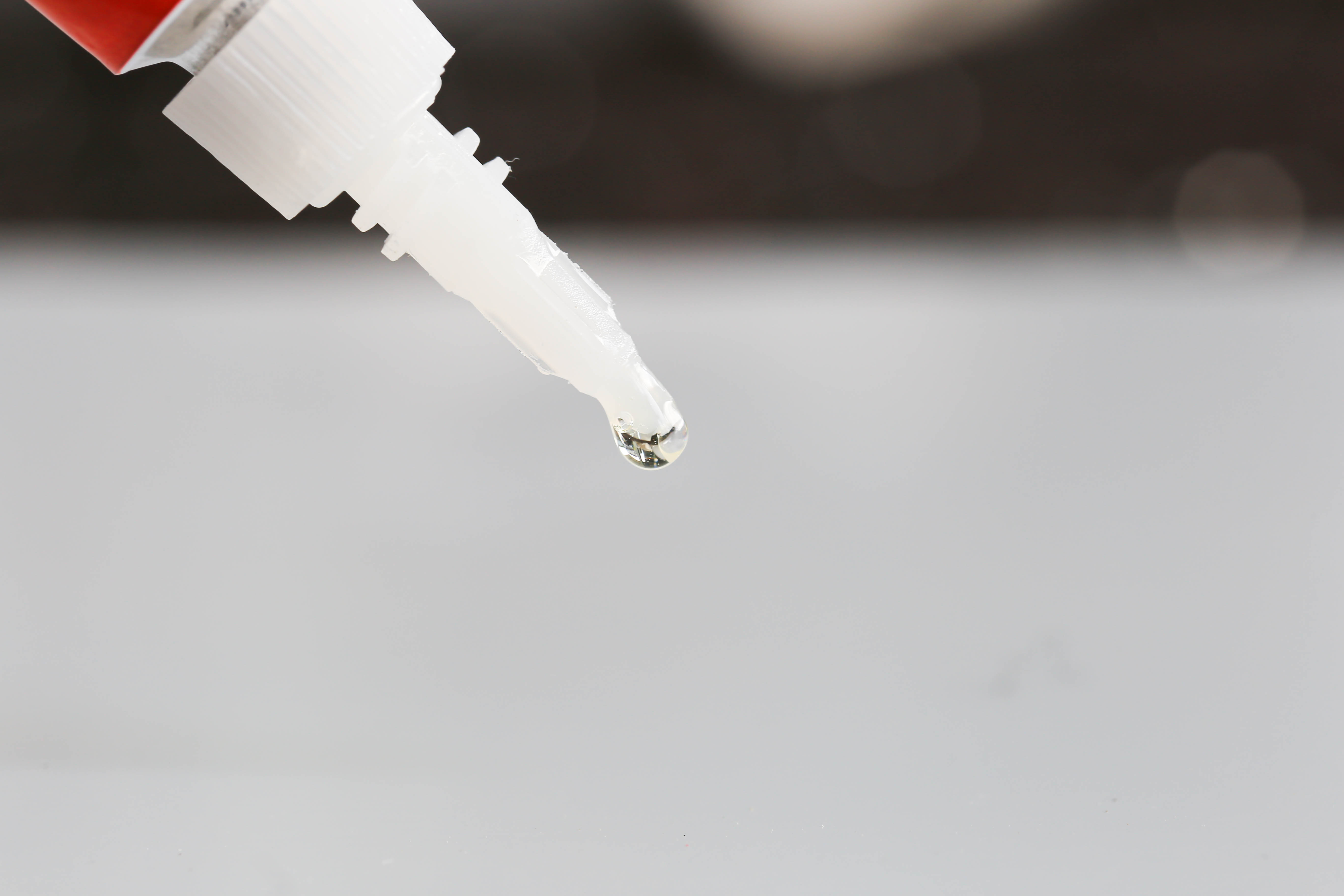 Tropfen Flüssigkleber an der Tülle einer weißen Flasche