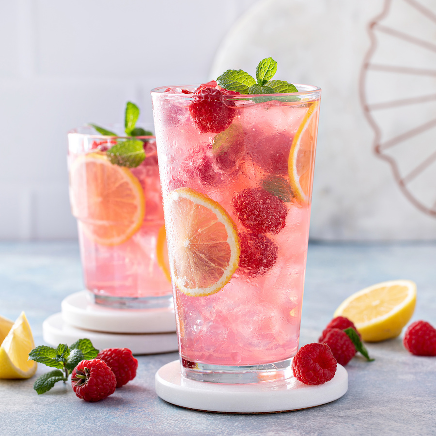 Zwei Gläser rosa Himbeerlimonade mit Eis, Zitronenscheiben und Minze