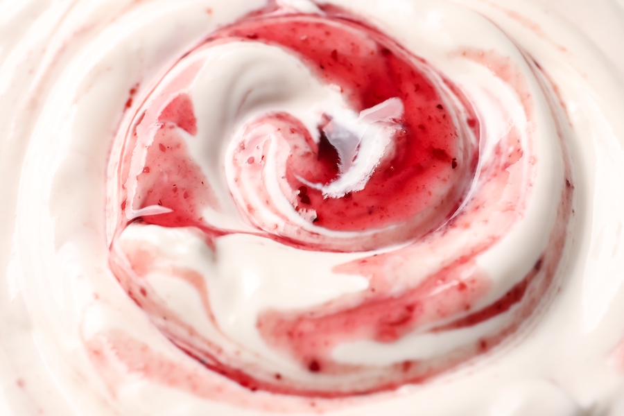 Nahaufnahme von cremigem Joghurt mit eingerührter roter Beerensauce