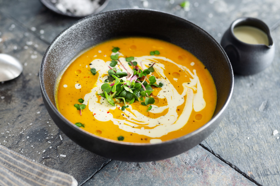 Schüssel cremige Kürbissuppe mit Sahne-Swirl und frischen Microgreens