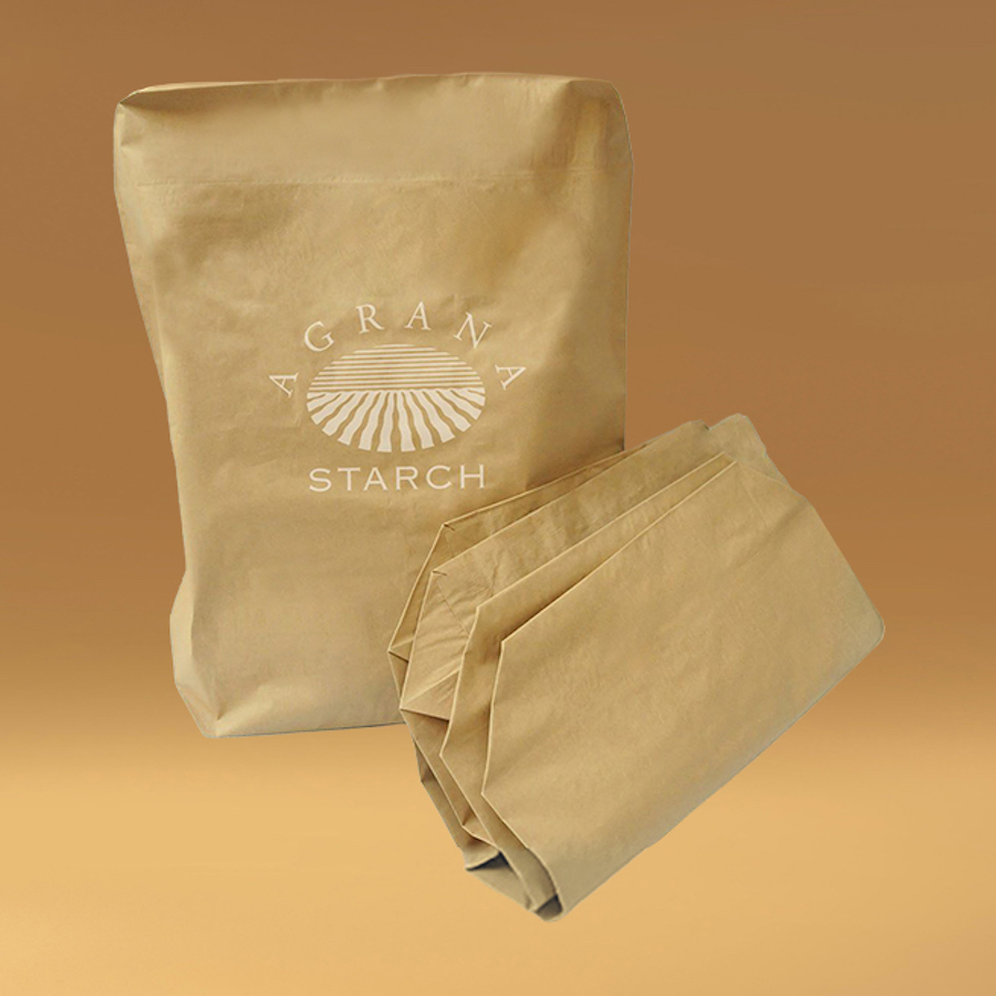 Braune Papiersäcke mit AGRANA-Starch-Aufdruck, einer stehend und einer gefaltet, vor orangem Hintergrund