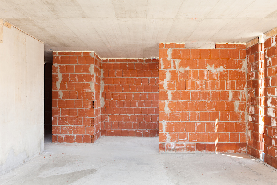 Rohbau-Innenraum mit roten Ziegelwänden sowie Betondecke und -boden
