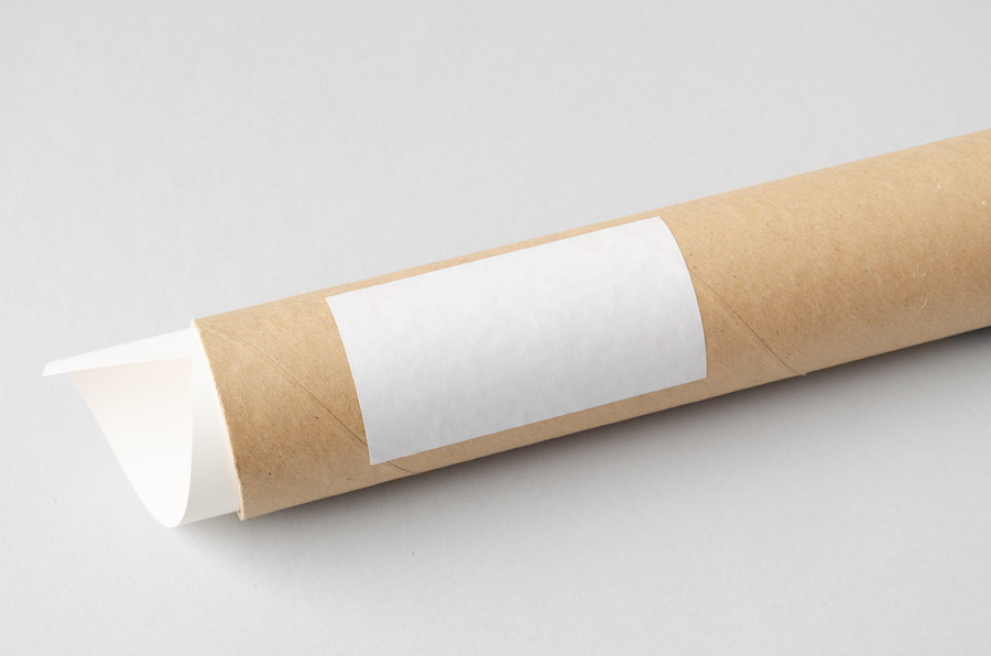 Versandrolle aus Kraftkarton mit leerem weißen Etikett und eingerolltem Papier