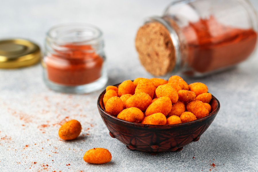 Schale mit Paprika-Erdnüssen, dahinter Gläser mit Paprikapulver