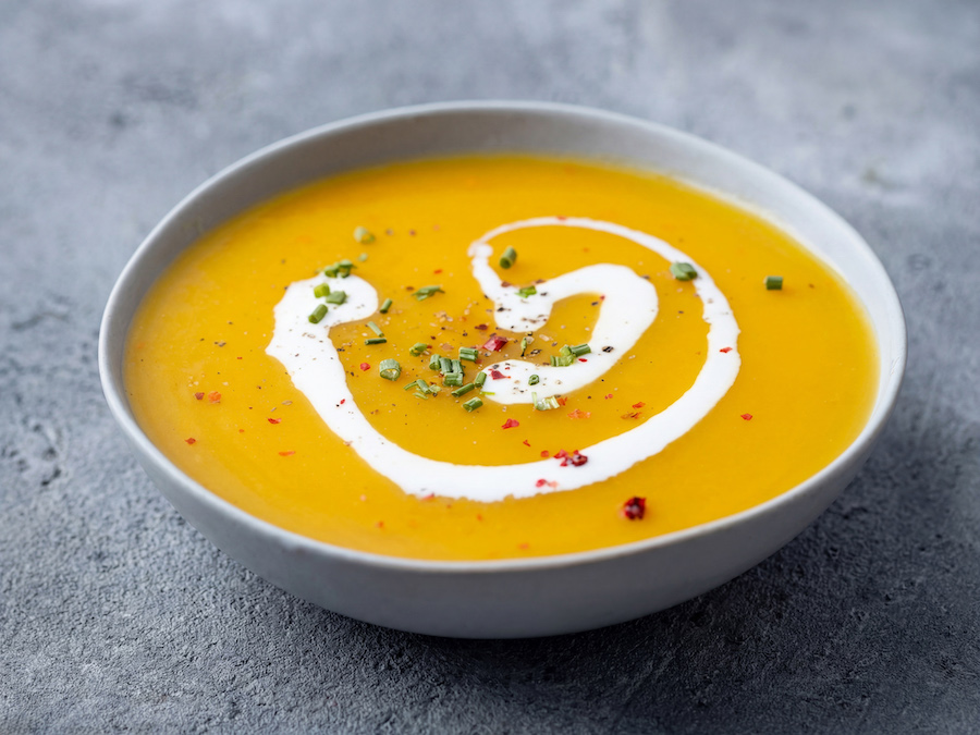 Schale Kürbiscremesuppe mit Sahneklecks, Schnittlauch und Chiliflocken
