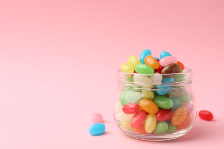 Glas gefüllt mit bunten Jelly Beans auf rosa Hintergrund
