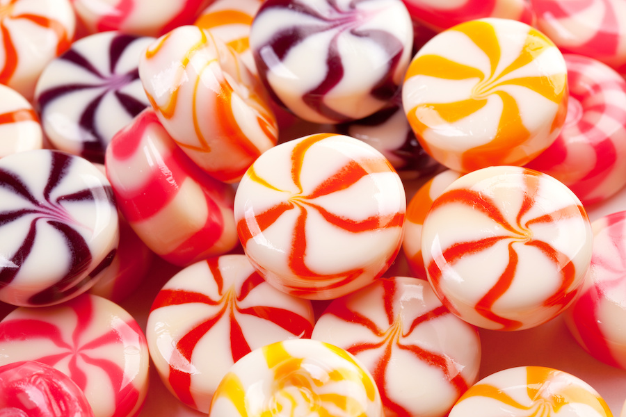 Nahaufnahme runder Hartbonbons mit roten, orangen und violetten Wirbelmustern