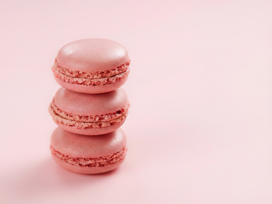 Stack of three pink macarons on a pink background