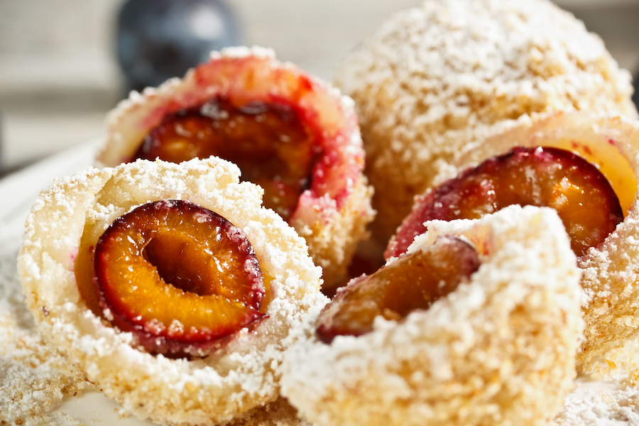 Plum dumplings cut open, coated in crumbs and powdered sugar