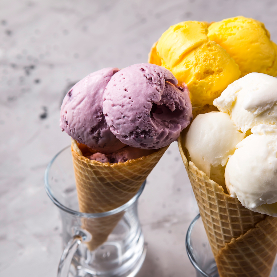 Waffeltüten mit Heidelbeer-, Mango- und Vanilleeis, in Gläsern stehend