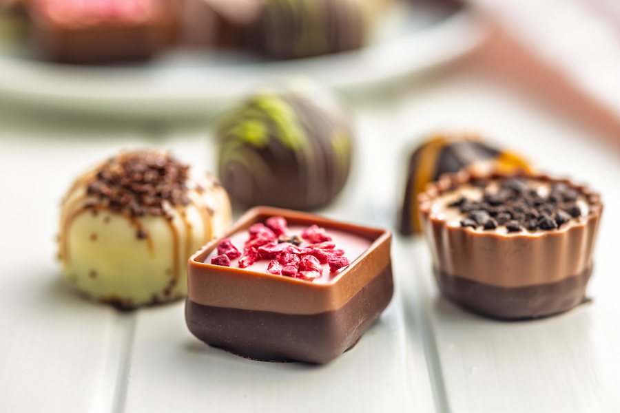 Chocolate bar cut in half showing a peanut and caramel filling, peanuts in shell alongside
