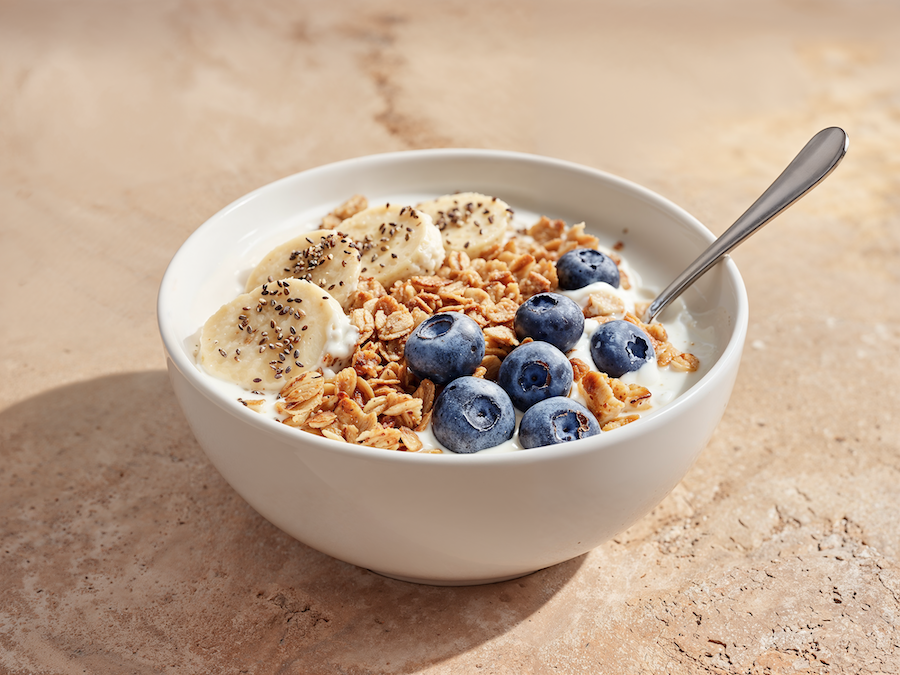 Bowl of yogurt with granola, banana slices, blueberries and chia seeds