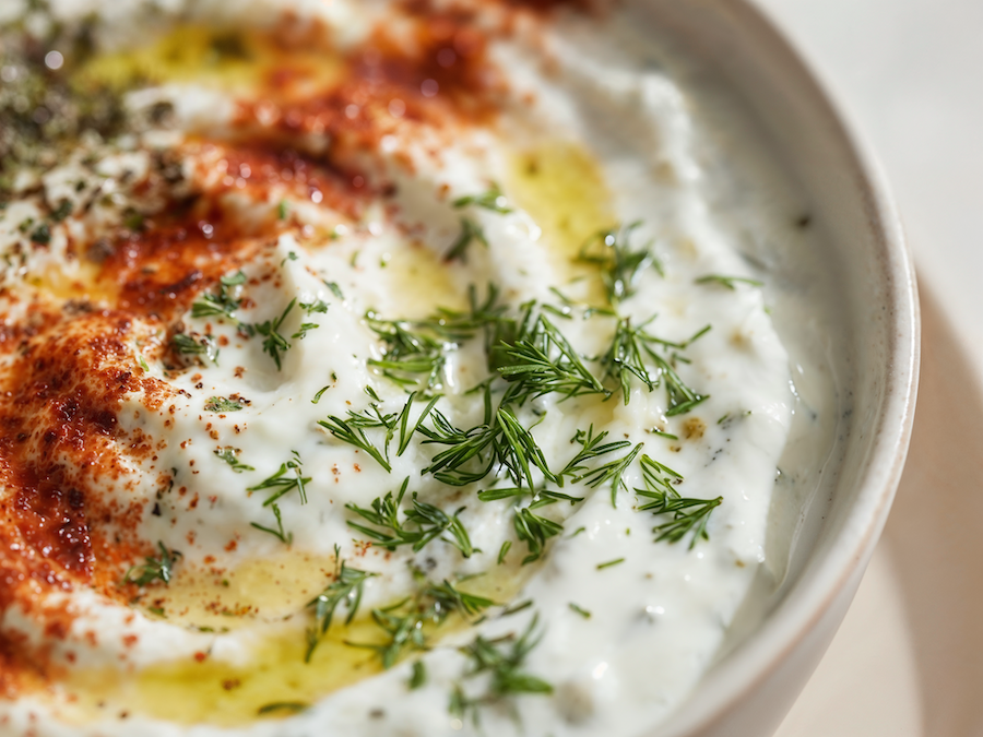 Close-up of a creamy white dip with dill, paprika and olive oil