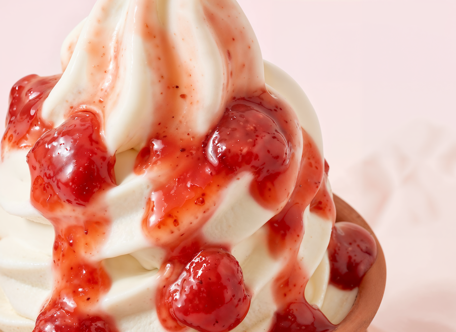 Nahaufnahme von Softeis mit Erdbeersauce und Fruchtstücken