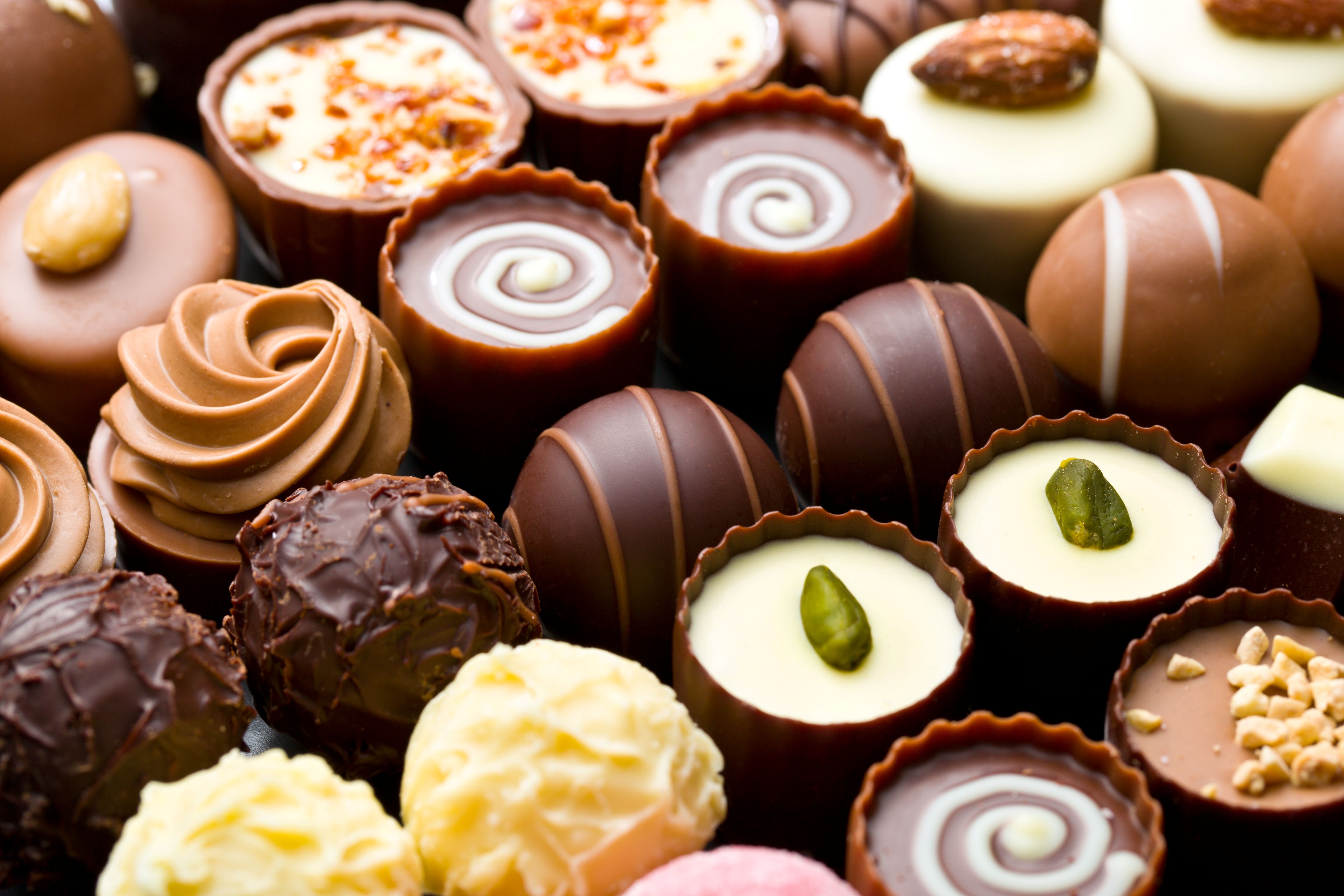 Sortierte Schokoladenpralinen mit Nüssen, Verzierungen und Pistazien in Papierförmchen