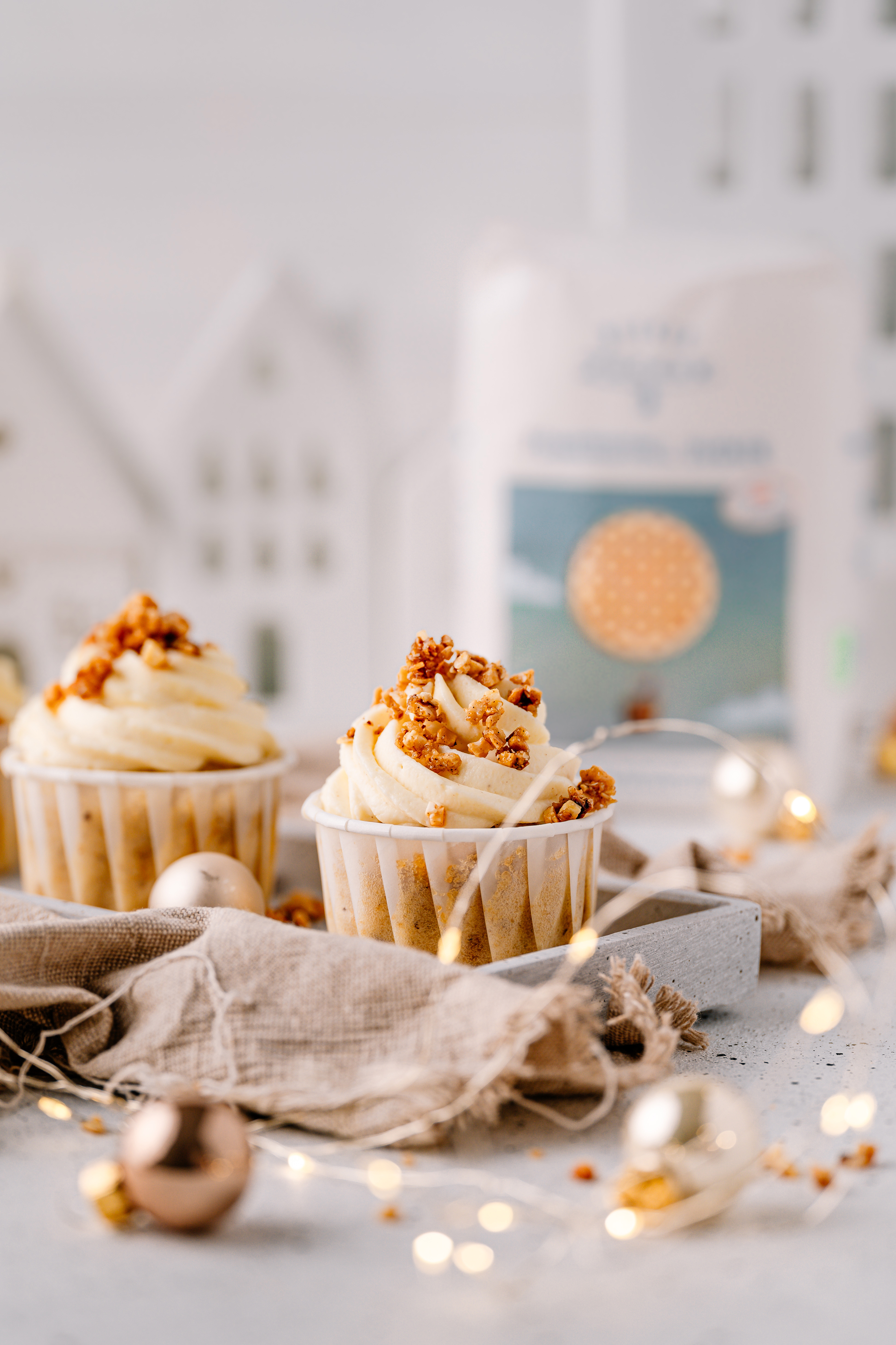 Cupcakes with swirled cream frosting and caramel brittle in a festive setting, sugar pack in the background