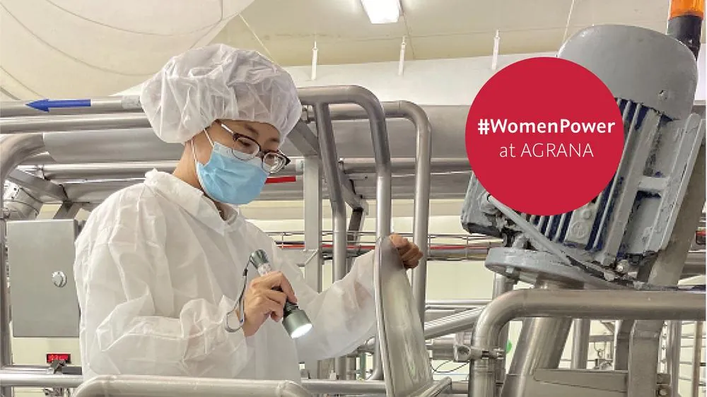 Wenxiu Ren, Quality Manager at AGRANA Dachang, in protective clothing on the production line, badge #WomenPower at AGRANA