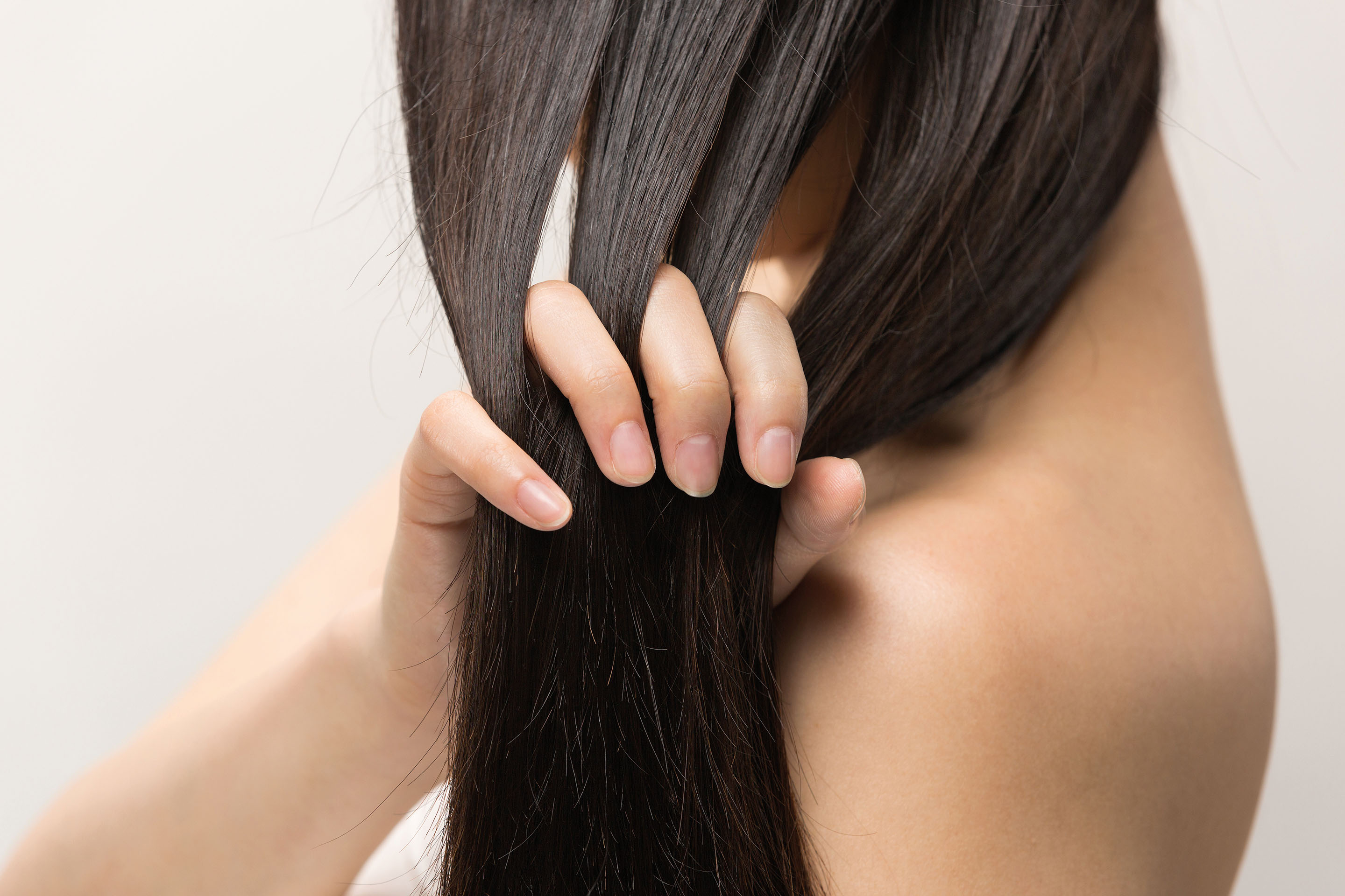 Frau fährt mit den Fingern durch langes, glänzendes dunkles Haar