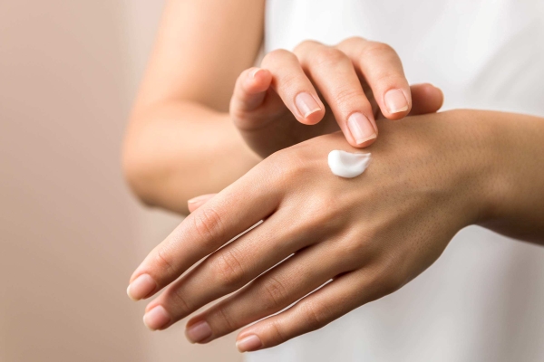 Woman applying a dab of white cream to the back of her hand