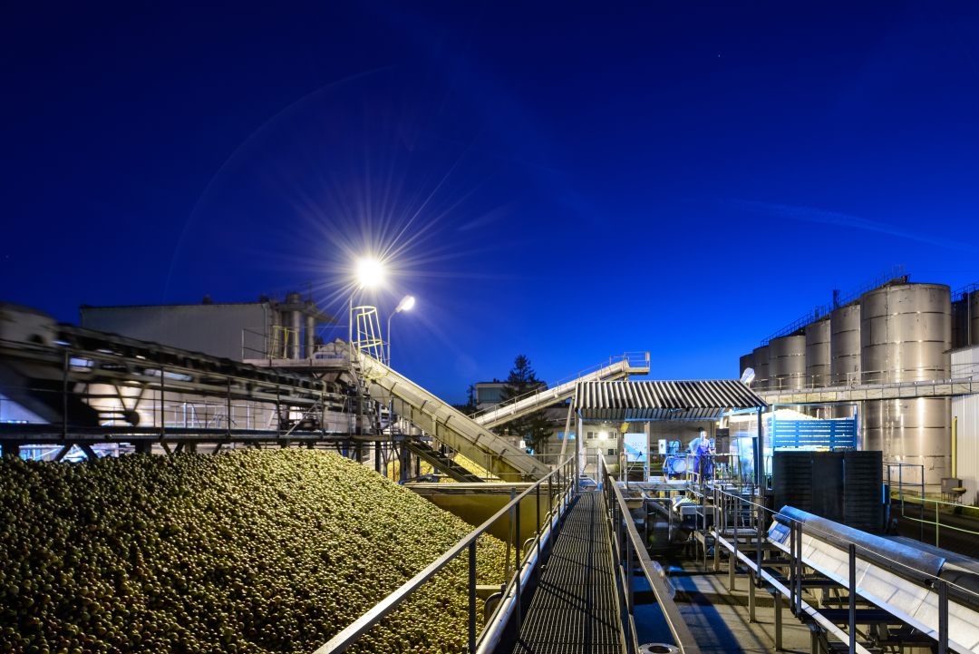 AUSTRIA JUICE Werk in Góra Kalwaria, Polen, Äpfel auf einem Förderband bei Nacht mit Tanks im Hintergrund