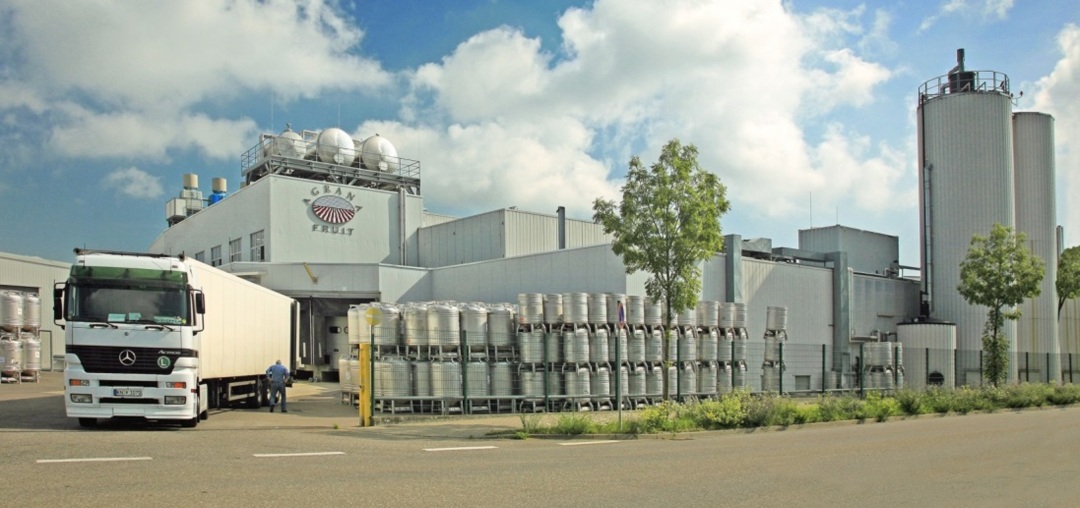 AGRANA Fruit Werk in Konstanz, Deutschland, mit Lkw und gestapelten Stahlfässern im Hof