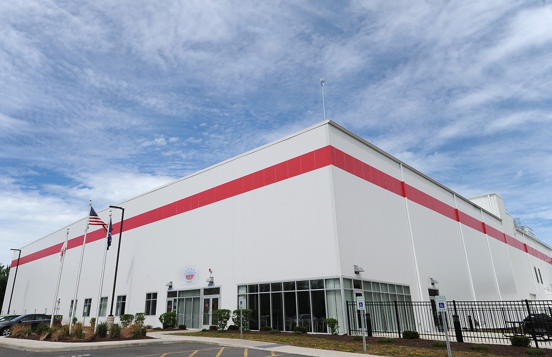 AGRANA Fruit US Werk in Baldwinsville, New York: weiße Halle mit rotem Streifen und US-Flagge am Eingang