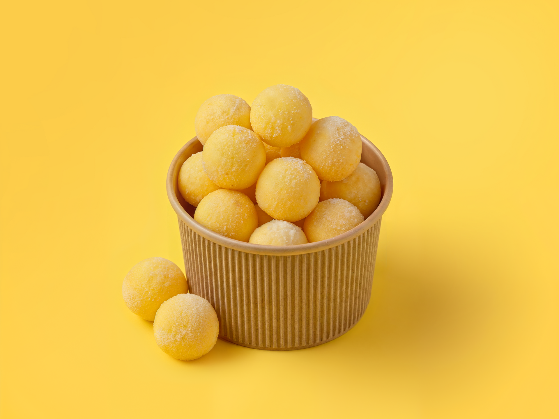 Bowl of golden coated peanut or cheese balls stacked on a yellow background