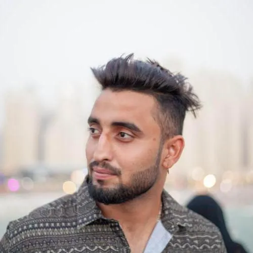 a man with a mohawk standing in front of a body of water