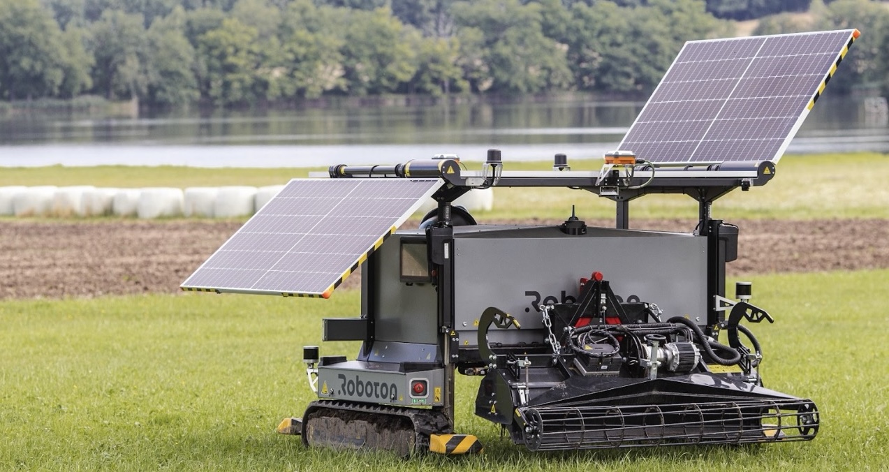 Agricultural robot with solar panels working among rows of green crops inside a greenhouse.