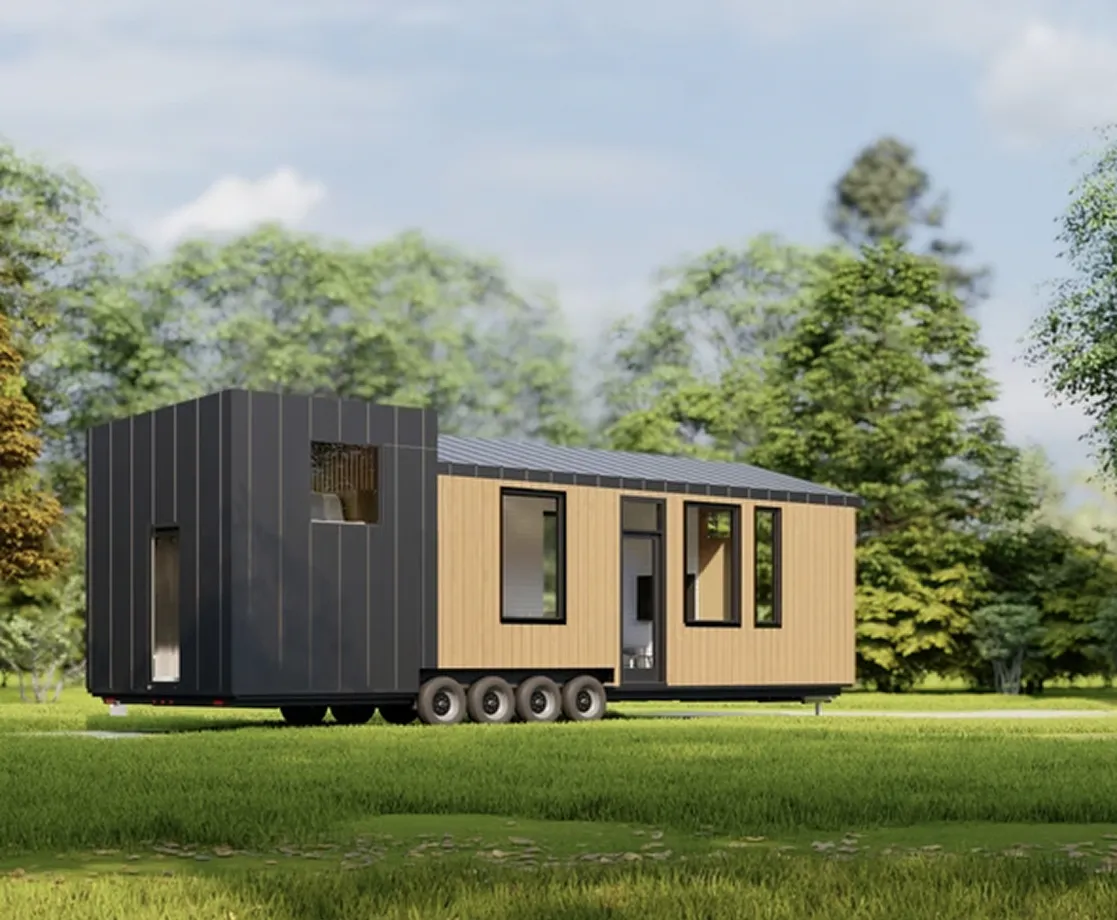 Modern tiny house on wheels with black and wood exterior panels situated on green grass with trees in the background.