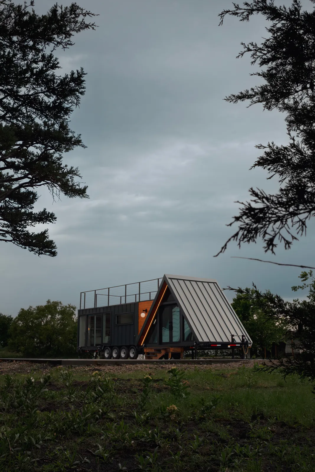 Casa Francesca, a finished Mainefactured A-frame tiny home with a rooftop deck, placed on open land among trees