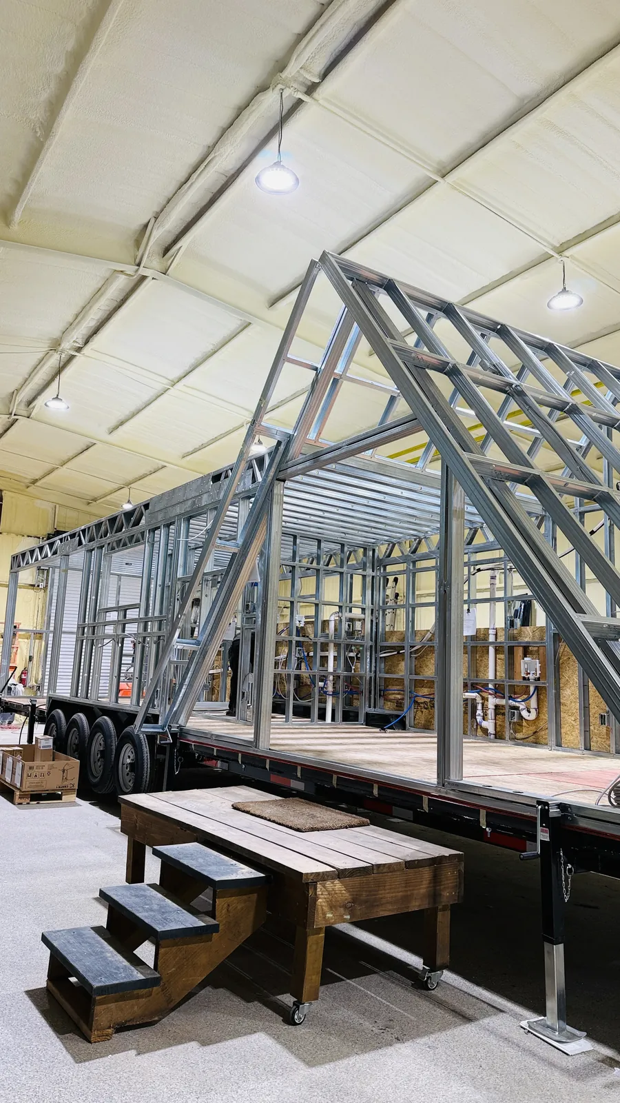 Steel A-frame tiny home structure on a trailer inside the Mainefactured shop