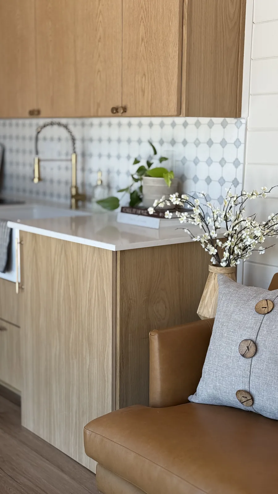 Light-oak kitchen with a leather sofa inside a Mainefactured tiny home