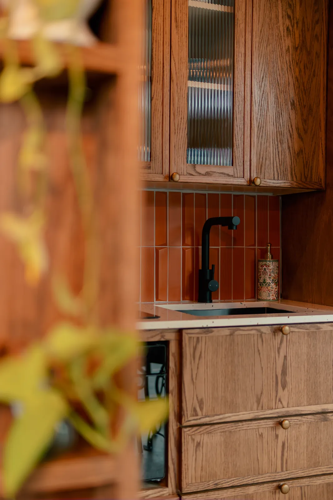 Wood kitchen with orange tile backsplash and a black faucet in a Mainefactured tiny home