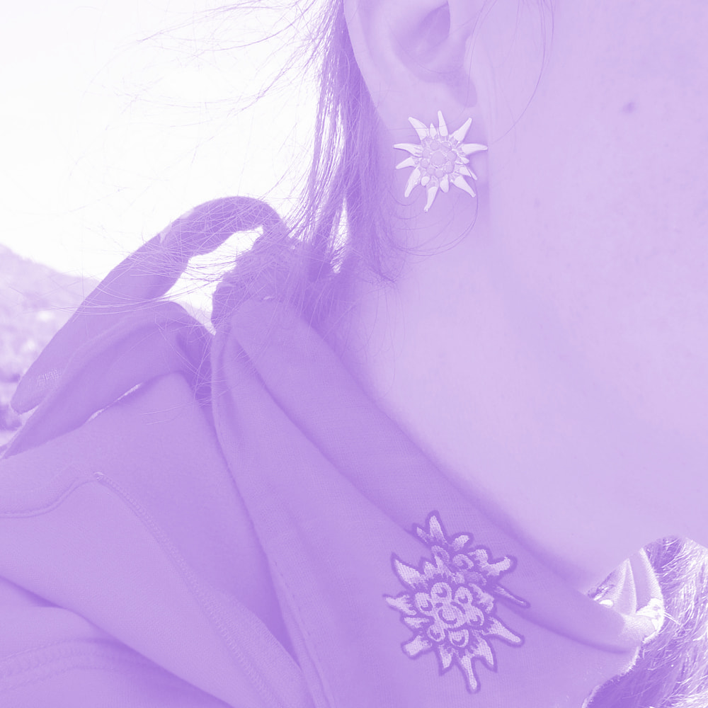 Close-up of a person's ear wearing a flower-shaped earring and a scarf with an embroidered flower design.
